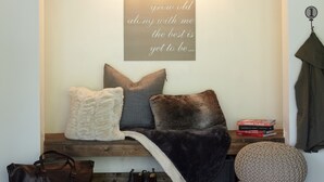 A cozy seating area with a bench, cushions, a decorative wall piece, and a hanging coat. - Large winter retreat just minutes from Dodge Ridge and Leland Snow Park (Mi-Wuk Village)