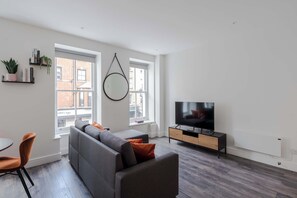 Ein modernes Wohnzimmer mit einer Couch, einem Fernseher und einem Essbereich.