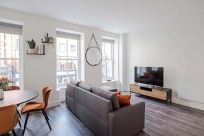Ein modernes Wohnzimmer mit einer Couch, Fernseher und Essbereich.