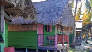 A thatched-roof hut with a green exterior and a small porch. - Private Ocean-Front Cabin with private bathroom on San Blas Island (Narganá)