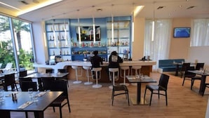 A modern bar area with a counter, shelves of bottles, and a TV screen. - Bw-1104b (Hallandale Beach)