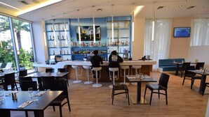 A modern bar area with a counter, bar stools, and a variety of bottles on shelves.