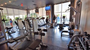 A gym with various exercise equipment, large windows, and a view of the outdoors.