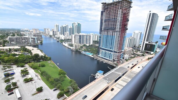 A high-rise building with a construction site, a river, and a bridge.