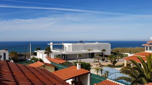 A modern house with a flat roof, solar panels, and a view of the sea. - Harmonic House with sea view (Atalaia Lourinhã)
