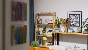 A dining area with a wooden table, chairs, a bookshelf, and various decorative items.