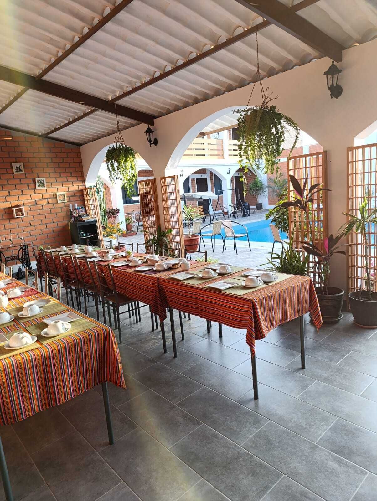 Un restaurant doté d’une terrasse, de murs en briques et de plantes suspendues. Les tables sont dressées avec de la vaisselle blanche.
