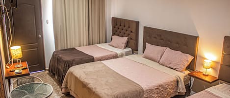 A hotel room with two beds, a small table, a chair, and a TV.