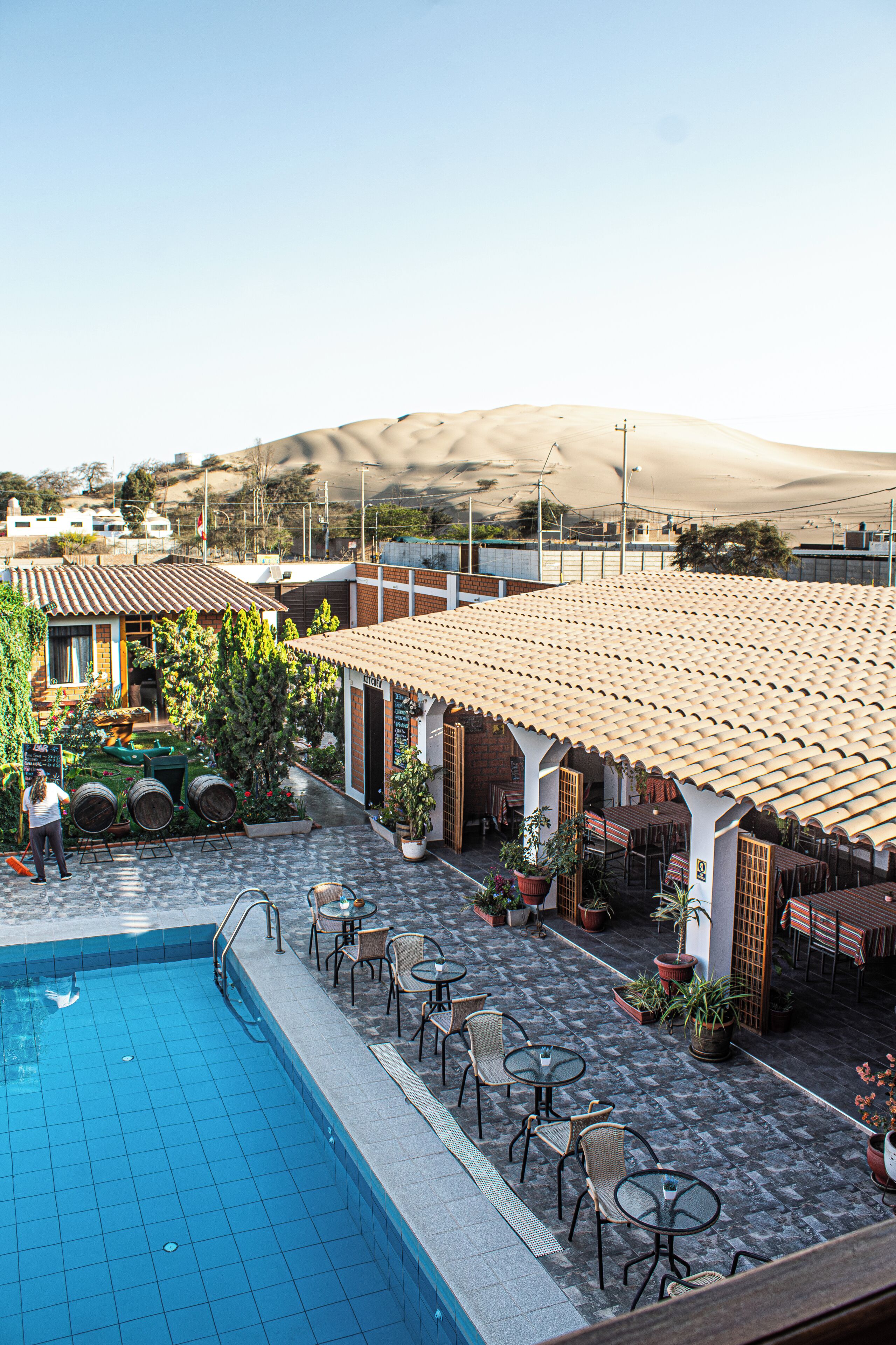 A pool area with tiled flooring, outdoor seating, and potted plants.