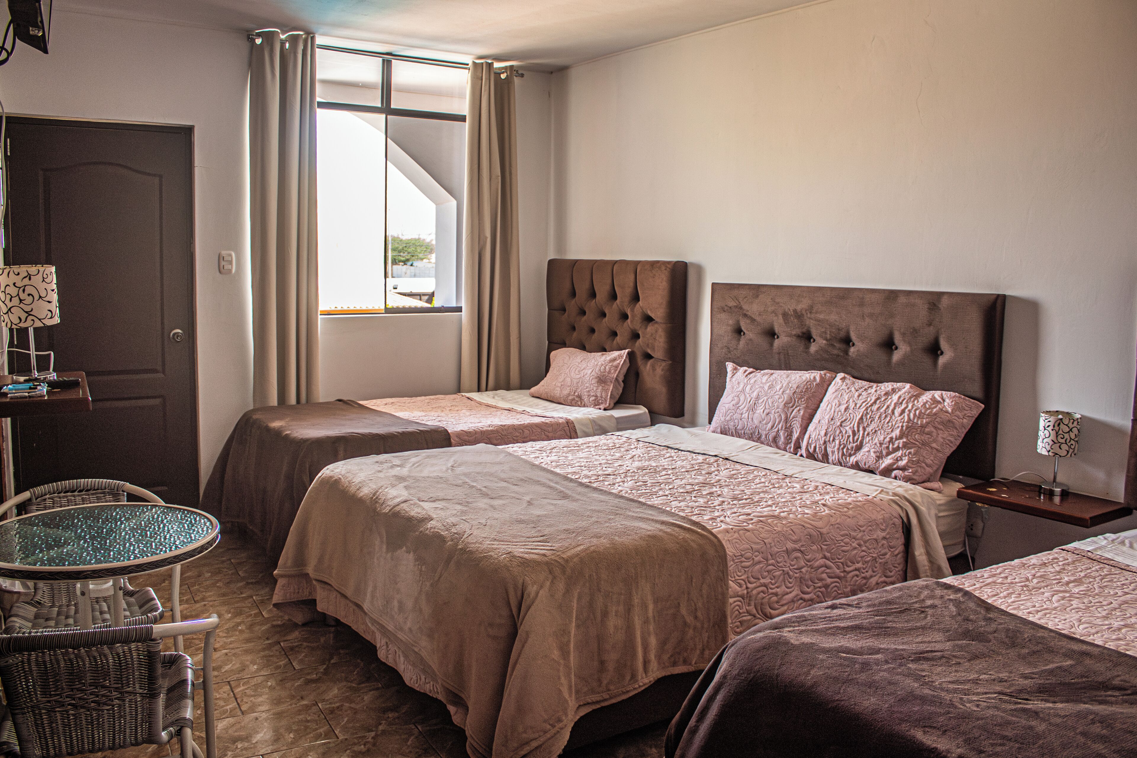 A hotel room with two beds, a small table, and a chair.