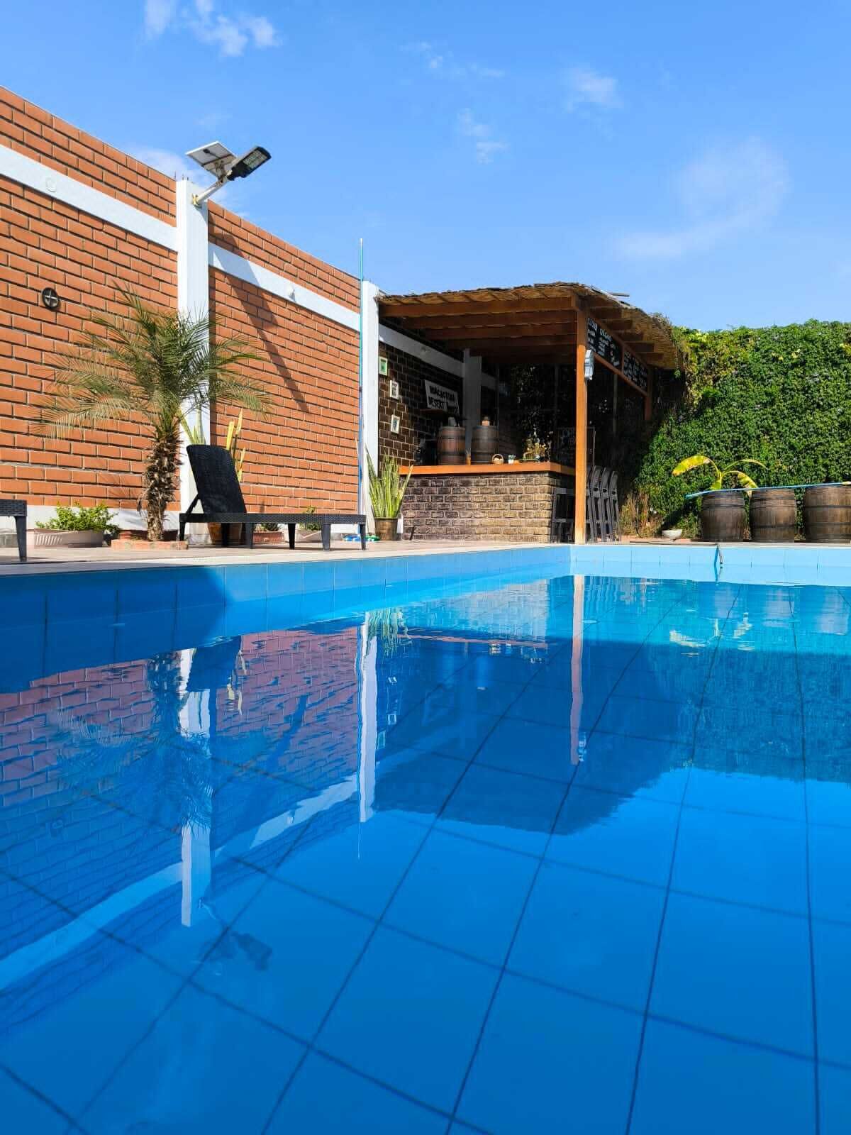 A swimming pool with a brick wall and a covered bar area.