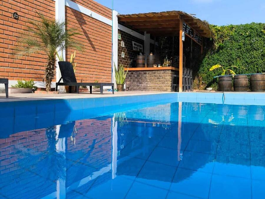 En swimmingpool med en murstensvæg og et overdækket barområde.