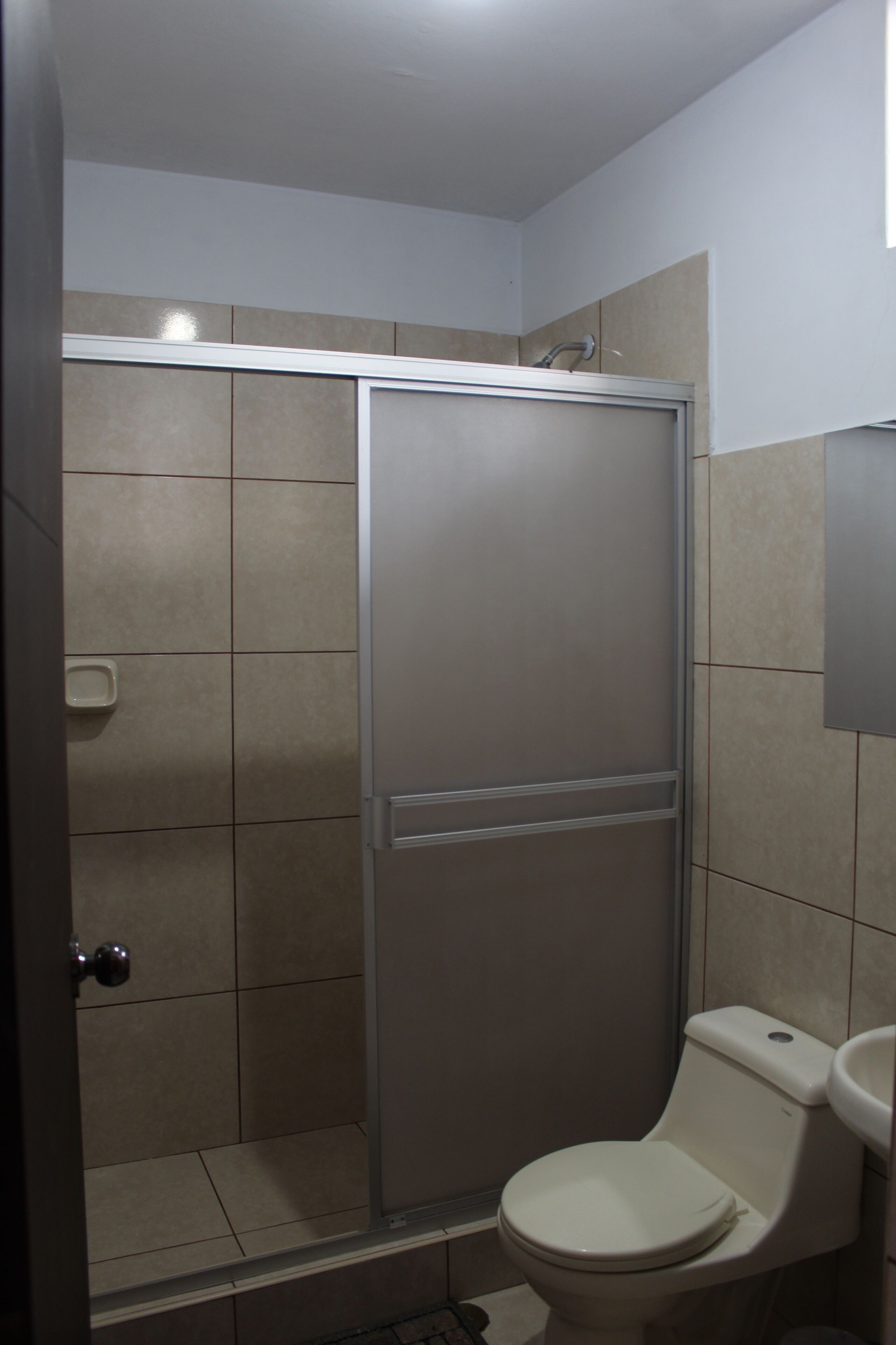 Un baño con cabina de ducha, inodoro y lavabo.