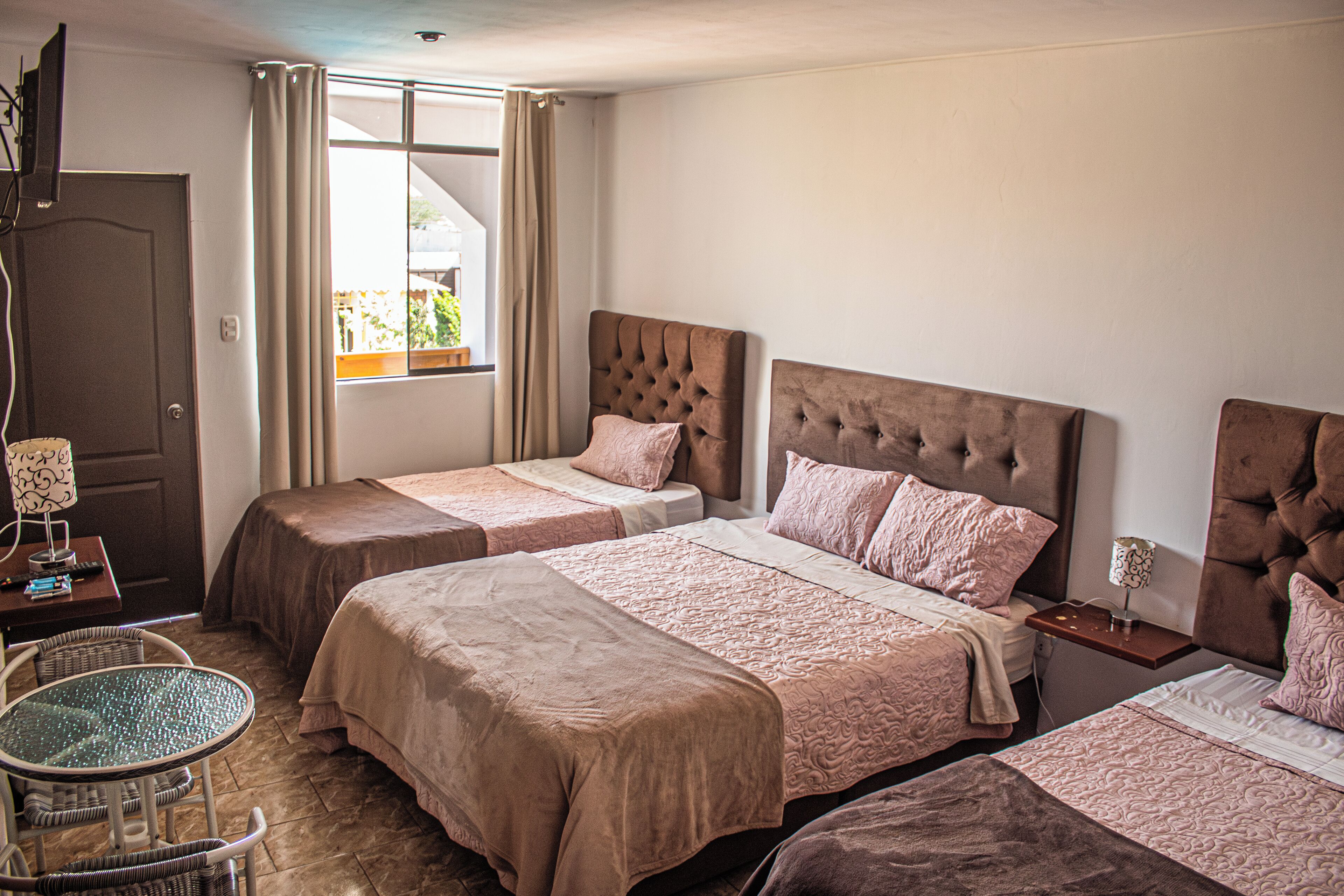 A hotel room with two beds, a small table, and a chair.