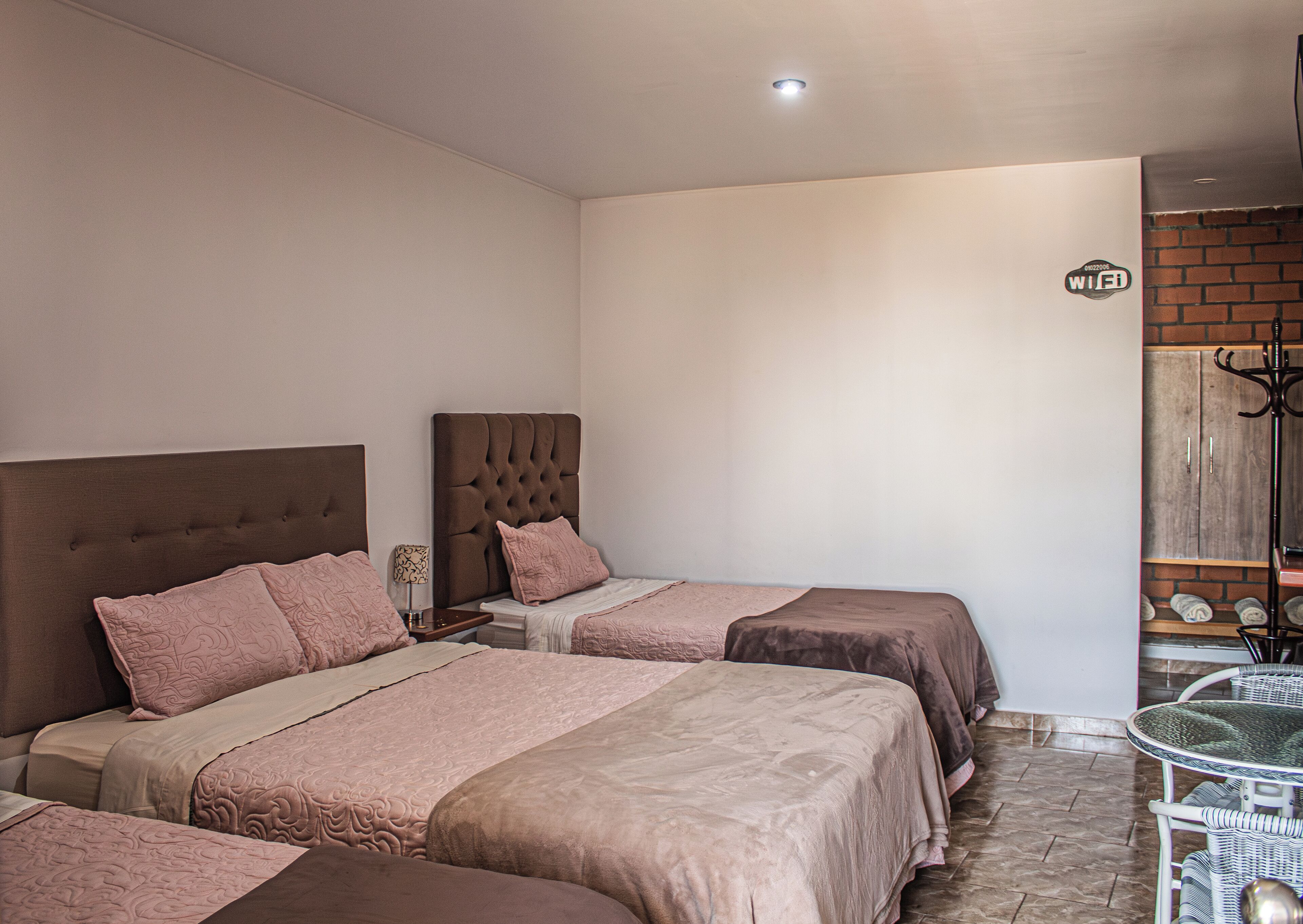 A hotel room with two beds, a small table, and a wardrobe.