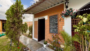 A brick building with a sign reading "KITCHEN" and a chalkboard menu listing breakfast items.