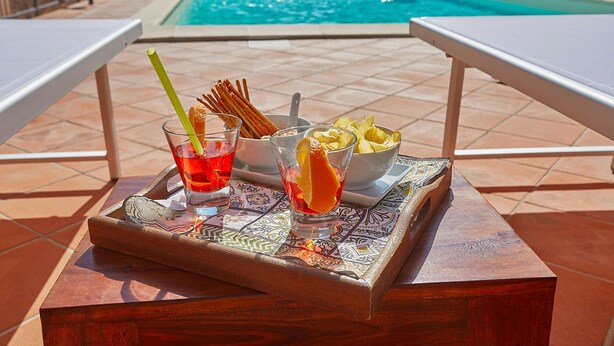 Una bandeja con bebidas y aperitivos junto a una piscina.