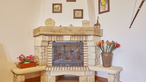 Una chimenea de piedra con repisa, un banco y un florero con flores.