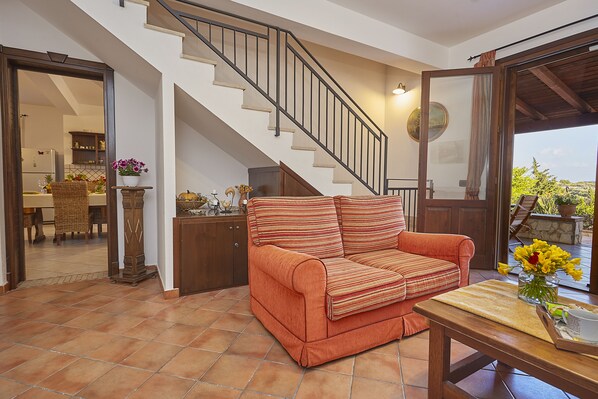 A living room with a sofa, a wooden table, and a staircase leading to an upper floor.