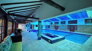 A large indoor swimming pool with a tiled floor and a glass ceiling. - Club Campestre El Bosque de la Villa (Villa de Leyva)