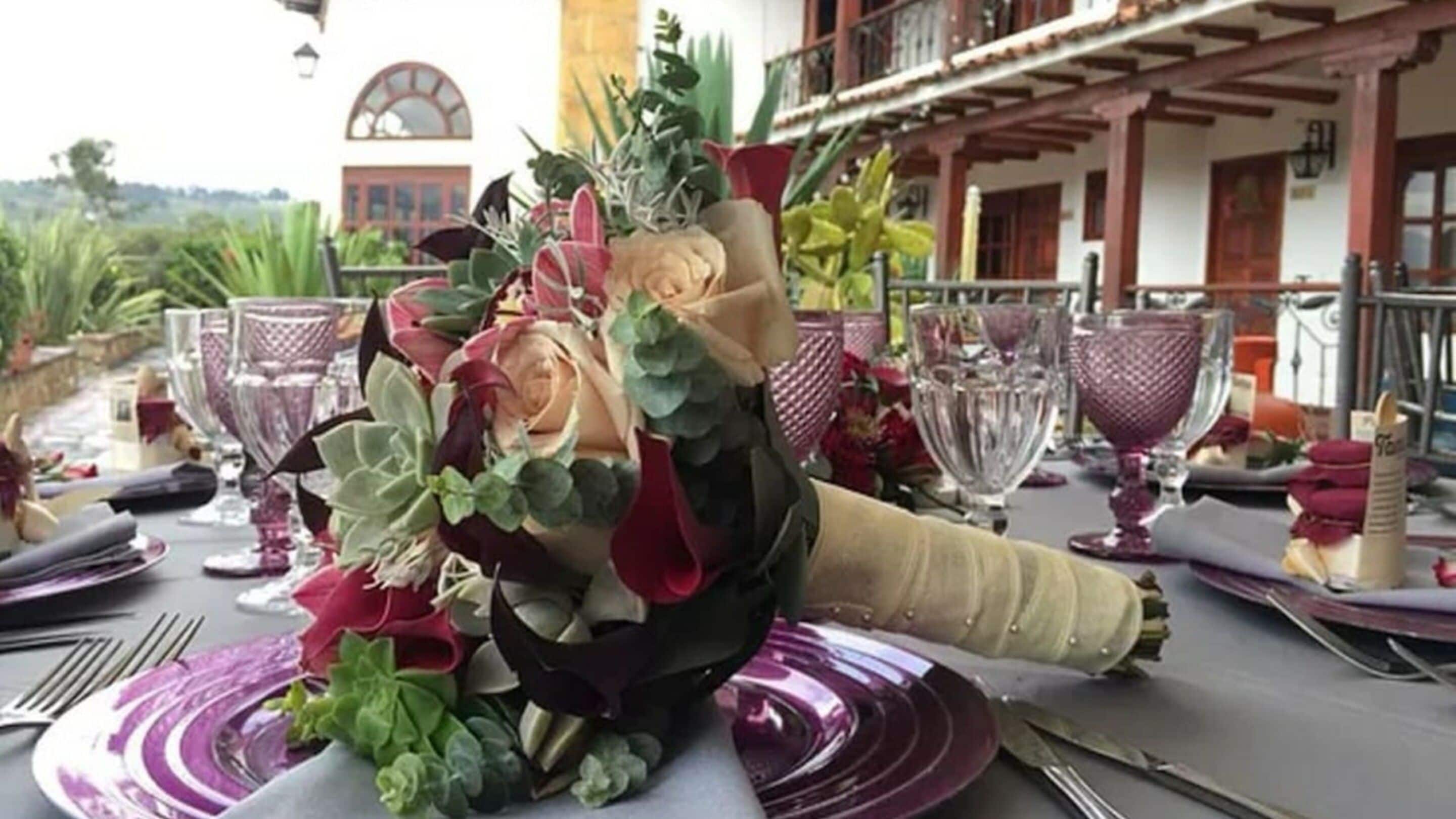 A table set with purple plates, silverware, and a centerpiece of flowers.