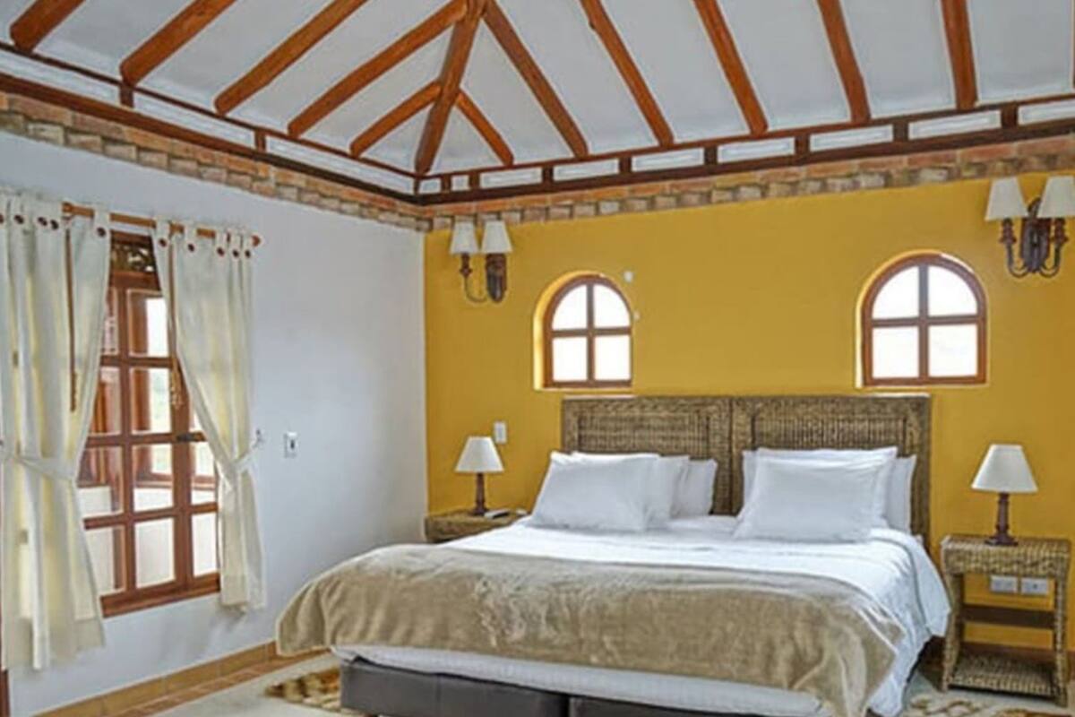 A bedroom with a bed, two bedside tables, a window, and a headboard.