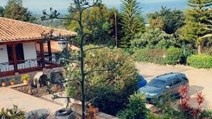 A courtyard with a fountain, potted plants, and a car parked outside. - Club Campestre El Bosque de la Villa (Villa de Leyva)