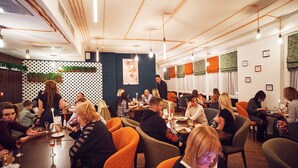 Un ristorante con diversi tavoli e sedie, una parete decorata con motivi e lampade a sospensione.