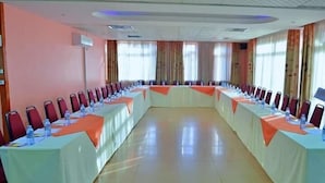 A conference room with a long table, red chairs, and a white tablecloth. - Strikers Hotel (Soroti)