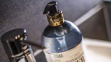 A bathroom sink with a modern faucet and a bottle of hand soap labeled "ginger & lime."