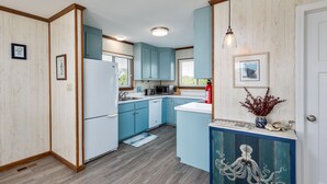 A kitchen with light blue cabinets, a white refrigerator, a microwave, and a sink. - 4752- Canopy Retreat, Walk to Beach | Quiet Kitty Hawk Retreat (Kitty Hawk)