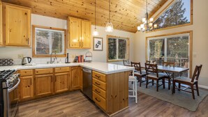 Una cocina con armarios de madera, una isla central y una zona de comedor con mesa y sillas.