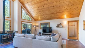 Un salón amplio con un sofá grande color gris, una chimenea y un televisor.