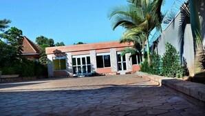 A building with a stone-paved entrance, large windows, and a red roof. - Mak Cottages (Kampala)