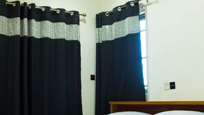 Un dormitori amb un llit, dos coixins i cortines negres amb detall platejat.