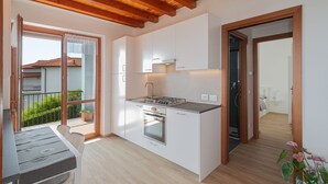A compact kitchen with white cabinets, a built-in oven, and a gas stove. - Panoramic View of Lake Maggiore Near Stresa • Private Garden & Parking (Levo di Stresa)