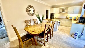 Un coin repas avec une table et des chaises en bois, un vase avec des plantes et un miroir décoratif au mur.