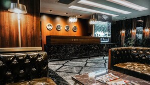 A reception area with a wooden reception desk, leather seating, a marble floor, and a television screen.