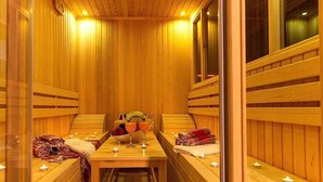 A sauna with wooden benches, a table with towels and fruit, and candles.