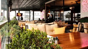 A modern cafe with a long counter, comfortable seating, and large windows.