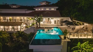 Ein modernes Haus mit Swimmingpool, Sitzgelegenheiten im Freien und einem gepflegten Garten.