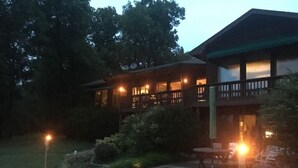 Een gebouw met twee verdiepingen, een balkon, een terras en een goed verlichte ingang.