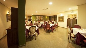 Un comedor con varias mesas y sillas, una pared de acento verde y obras de arte enmarcadas en las paredes.