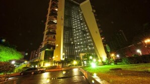 Un moderno edificio de gran altura con fachada de vidrio y un diseño arquitectónico único que presenta un costado inclinado.