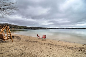 A beach with a swing set and two chairs near the water.