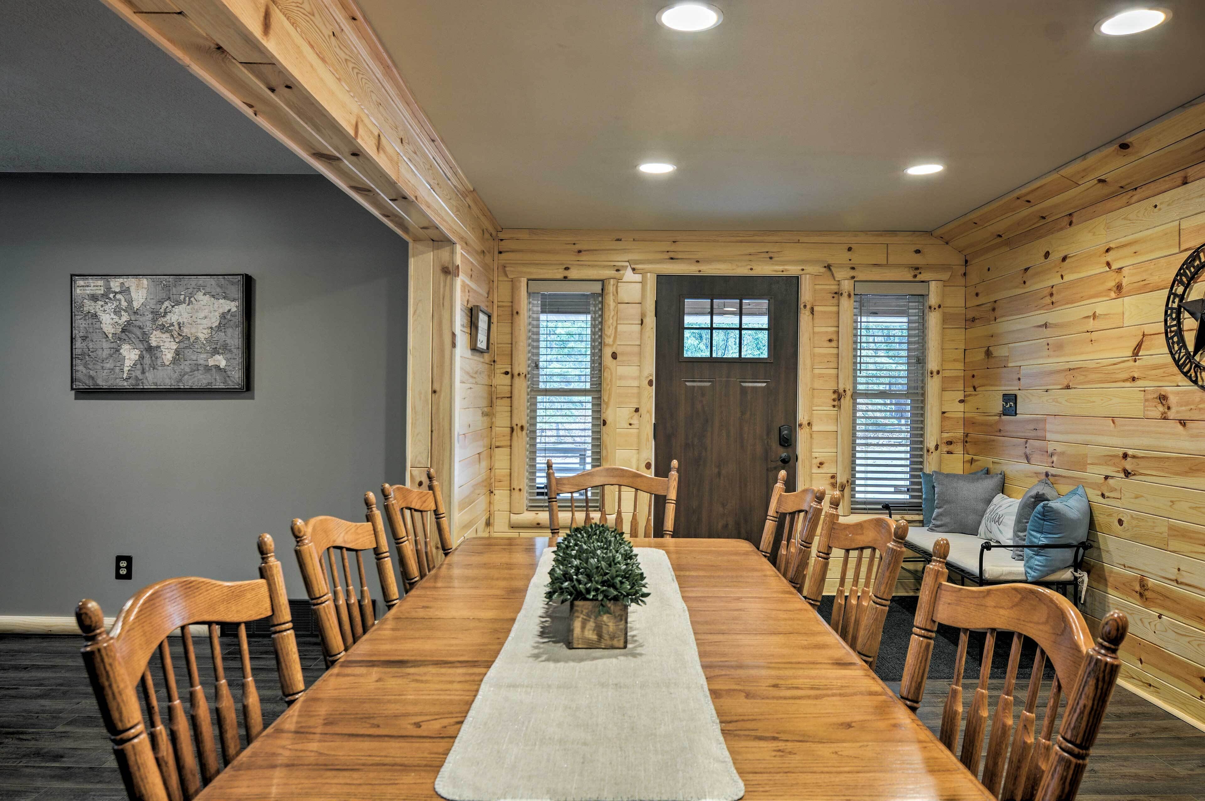 Comedor de madera con una larga mesa, sillas, un pequeño centro de mesa con planta y un mapa mundial en la pared.