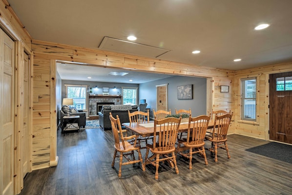 A spacious dining area with a wooden table and chairs, a fireplace, and a view of the outdoors.
