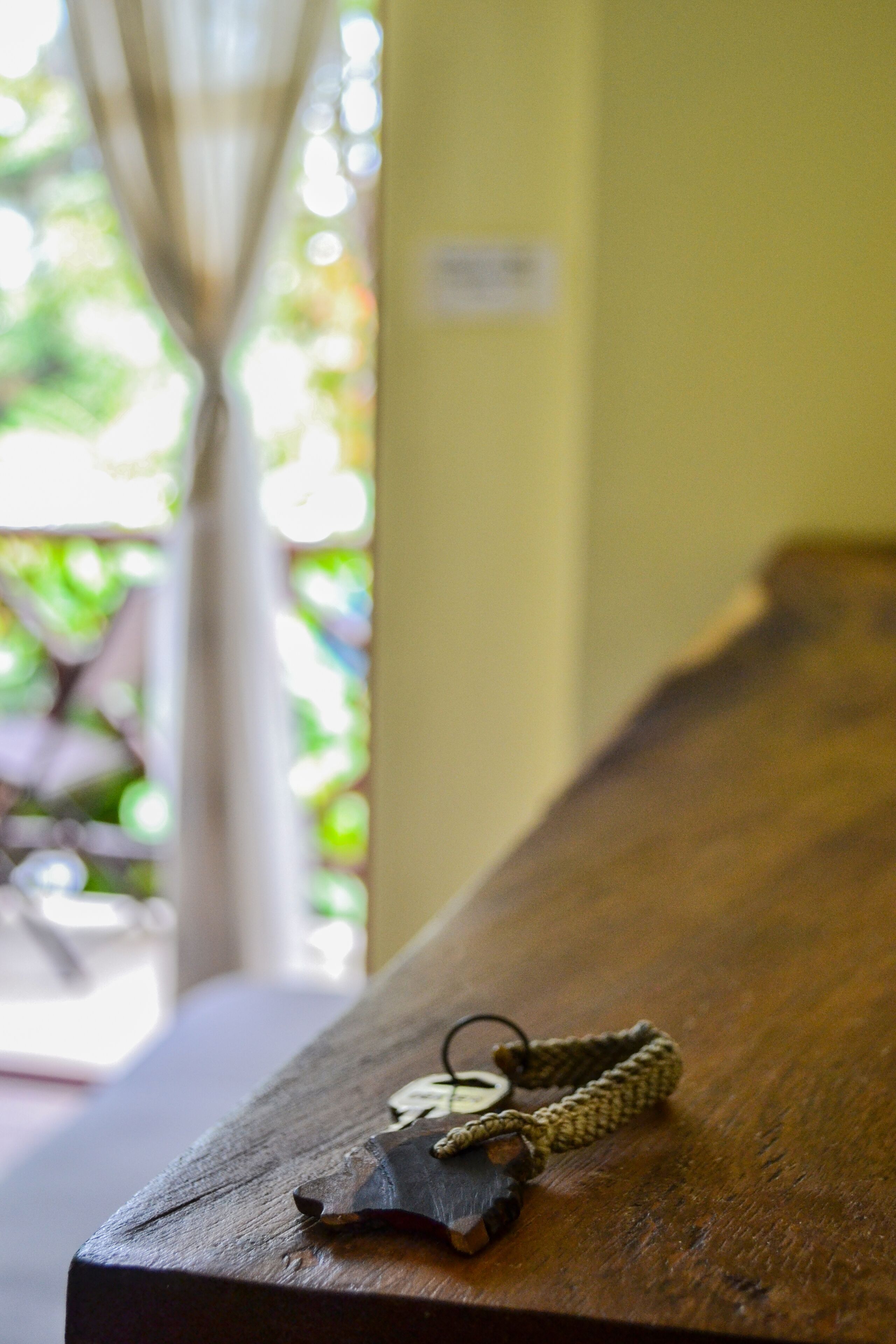 Una mesa de madera con un bolso tejido y un llavero.