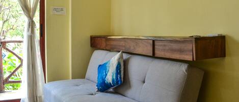 Una habitación con un sofá gris, un cabecero de madera y una ventana con cortinas.