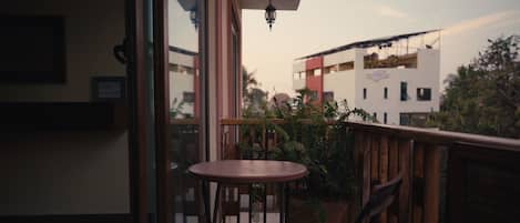 A balcony with a wooden railing, a small round table, and a chair.